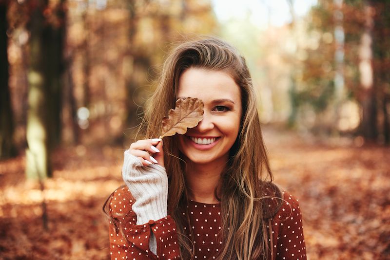 beautiful-woman-covering-eye-with-autumnal-leaves.jpg