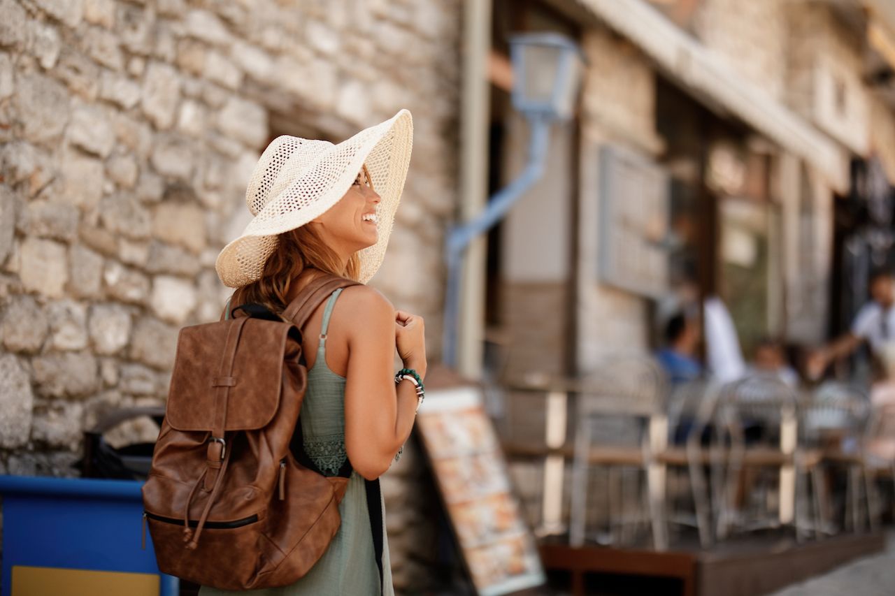 happy-female-tourist-with-back-back-taking-walk-exploring-town-summer-vacation.jpg