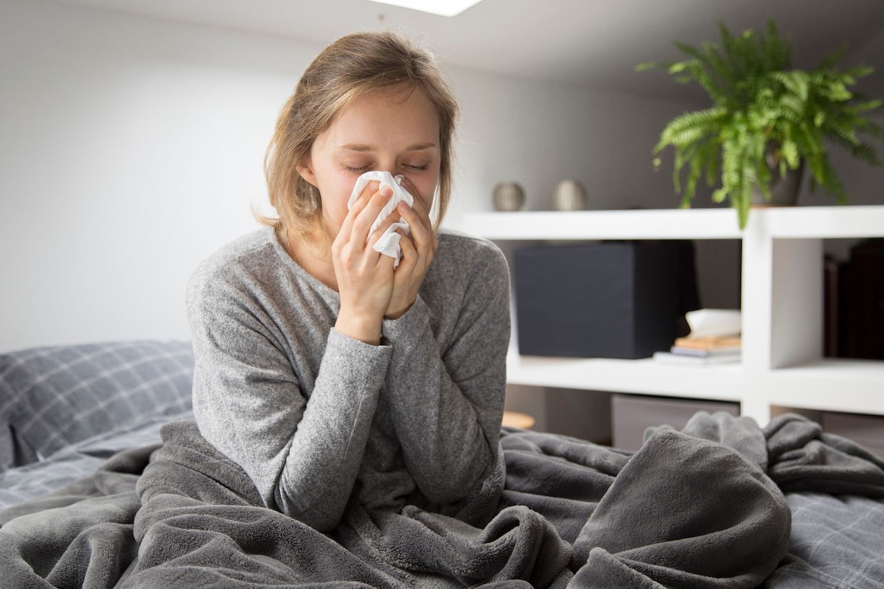 sick-woman-sitting-bed-blowing-nose-with-napkin.jpg
