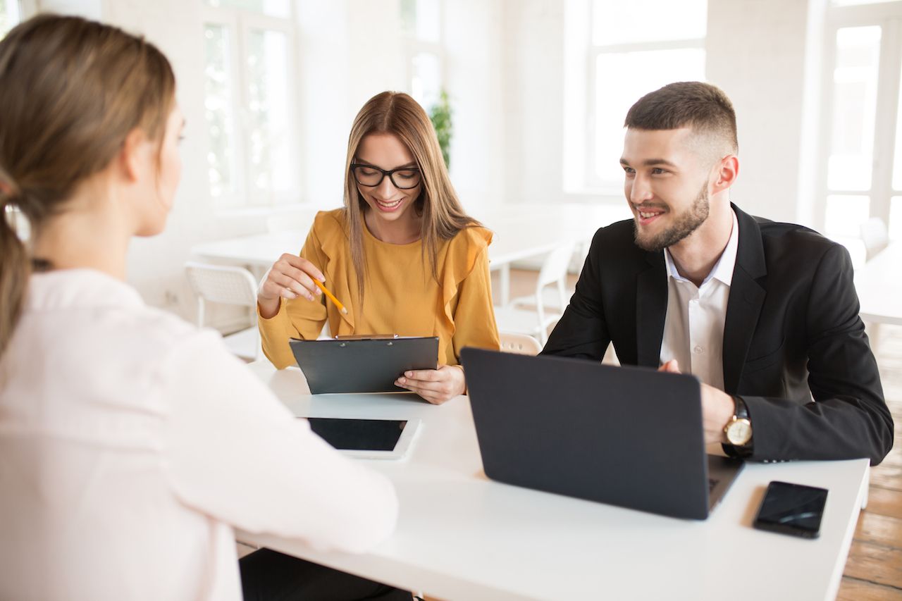 smiling-business-man-with-laptop-business-woman-eyeglasses-with-folder-hand-while-happily-talking-with-applicant-about-work-young-joyful-employers-spending-job-interview-modern-office.jpg