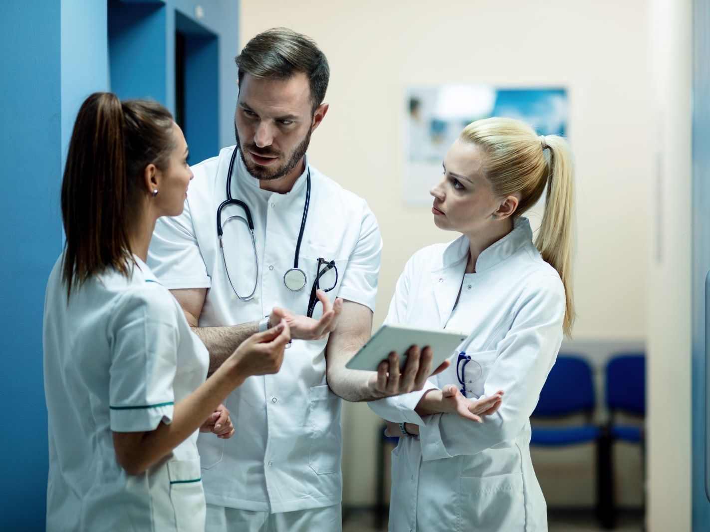 team-doctors-going-through-electronic-medical-reports-touchpad-talking-hallway-clinic.jpg