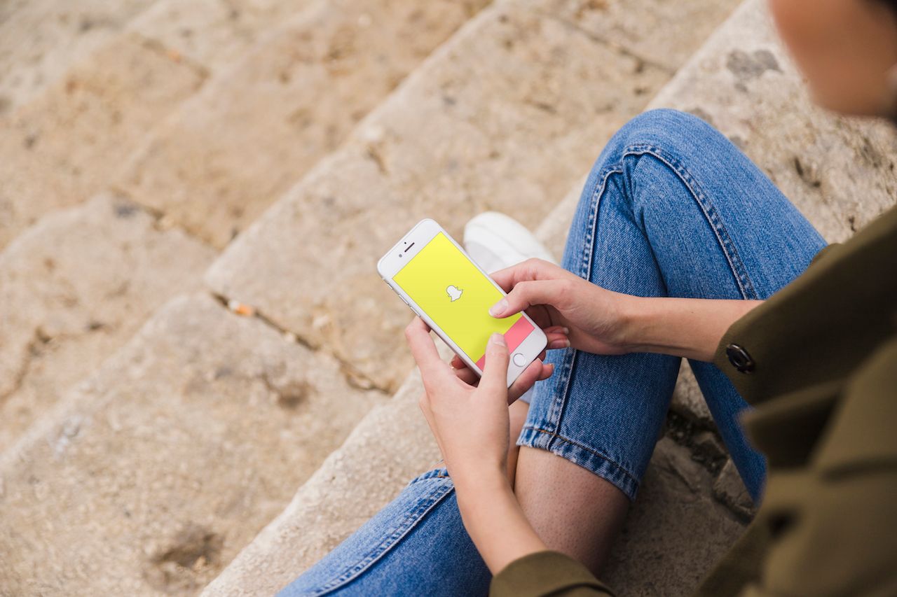 woman-sitting-staircase-using-snapchat-app-smartphone.jpg