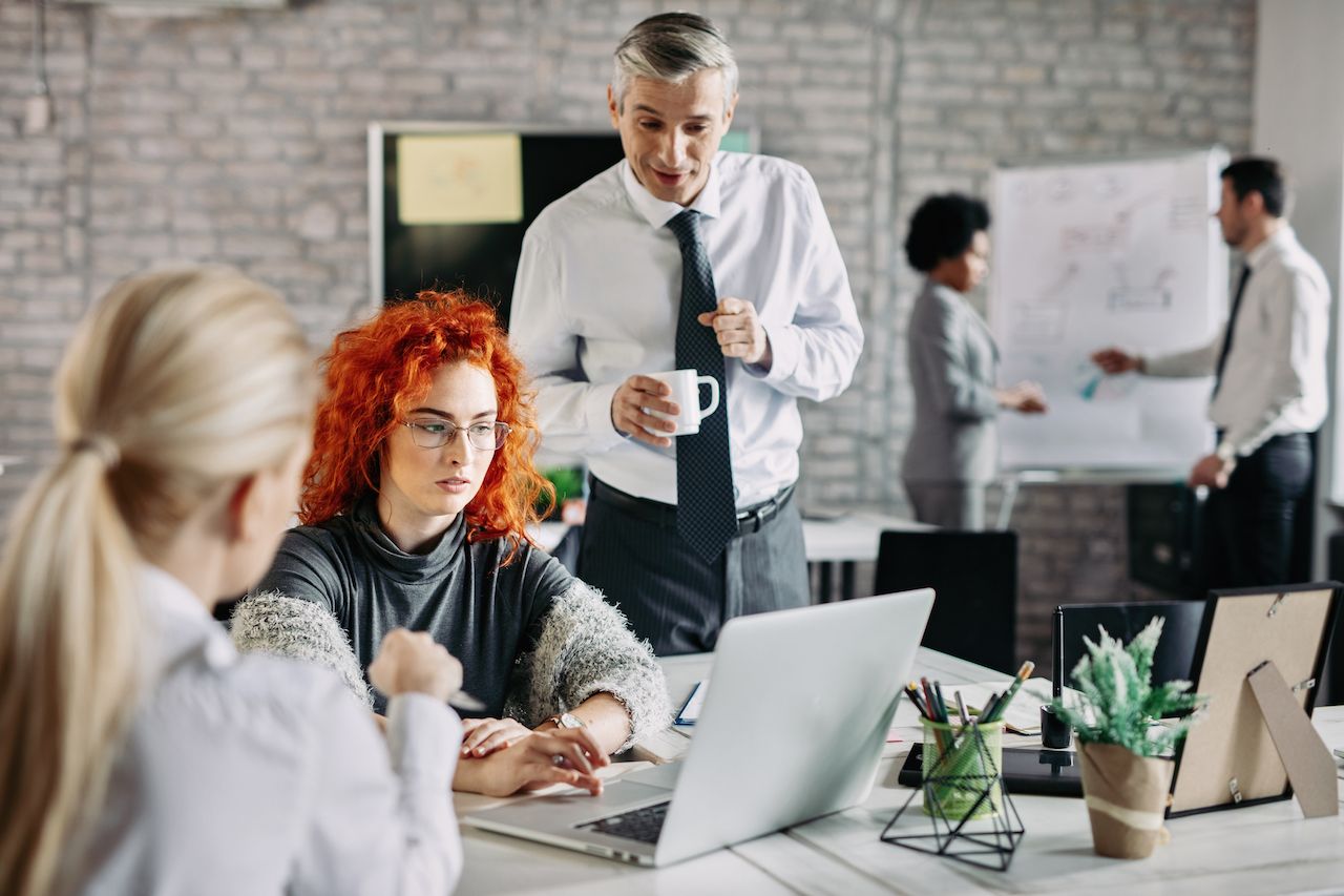 young-businesswoman-using-computer-while-having-meeting-with-colleagues-office-there-are-people-background.jpg