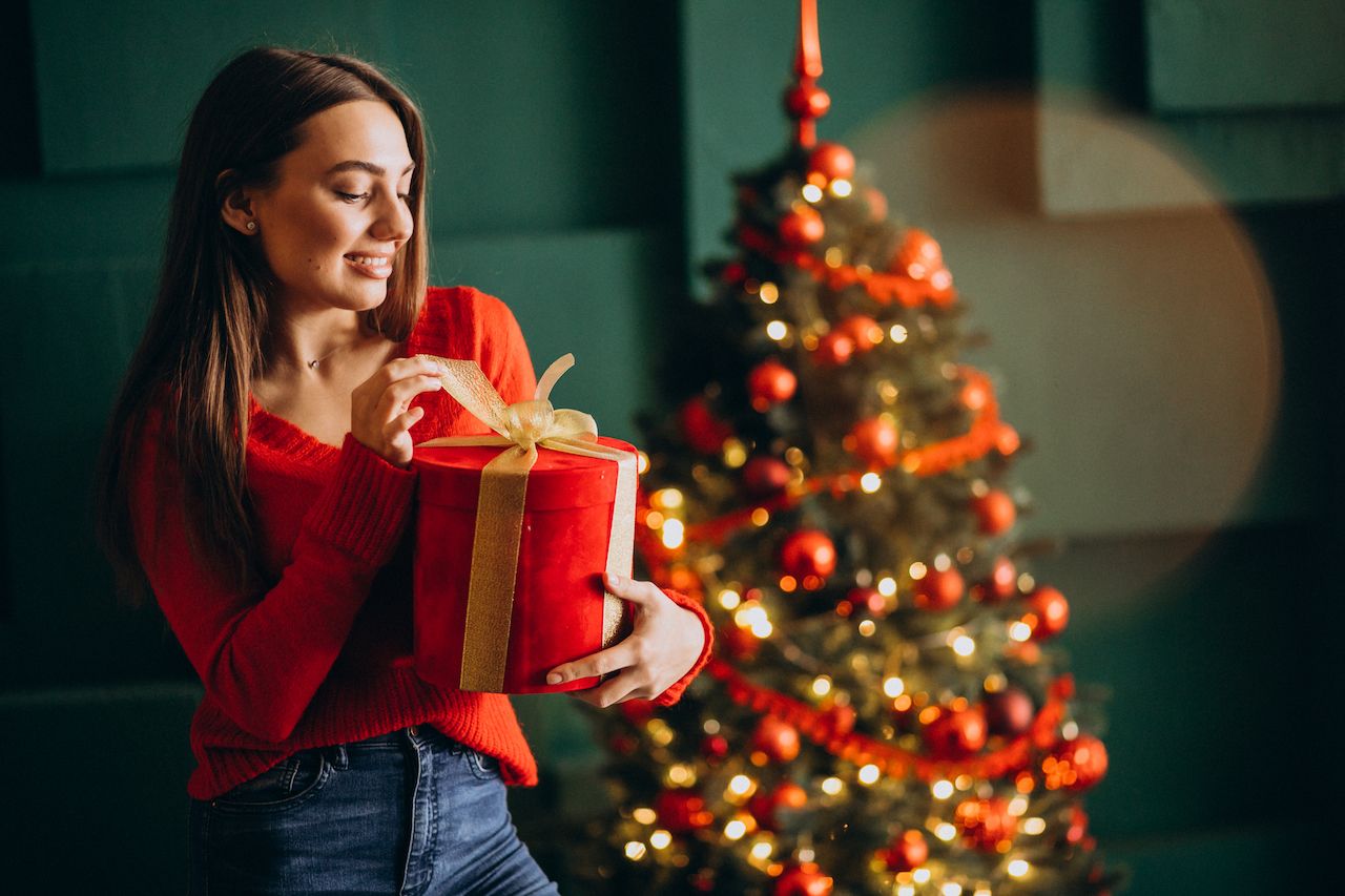 young-woman-unpacking-christmas-present-by-christmas-tree.jpg
